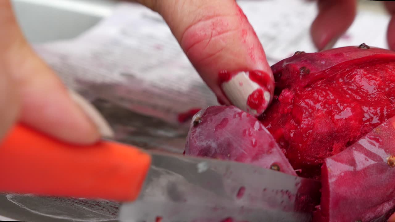 vista lateral de la mujer cortando y pelando la fruta jugosa de tuna rosa