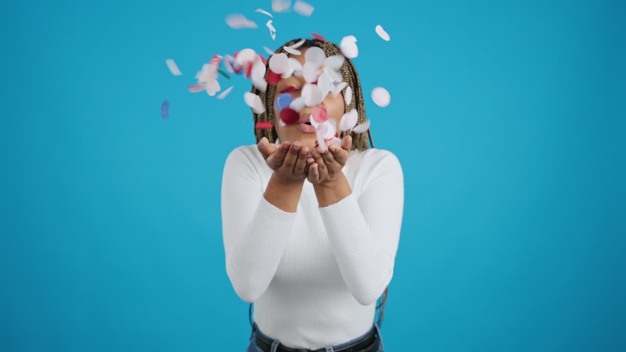 Happy young woman celebrating with colorful confetti on a blue background