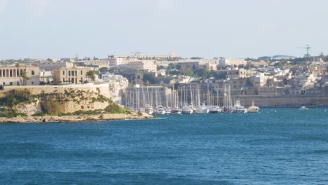 Many-docked-sailboats-swinging-on-waves-of-blue-water-near-Malta-island,-distance-view