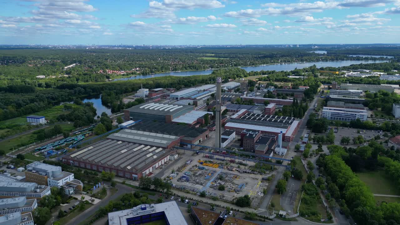 Hennigsdorf industrial area with modern offices, old factory buildings and chimneys under blue sky. Best aerial view flight fly reverse drone
