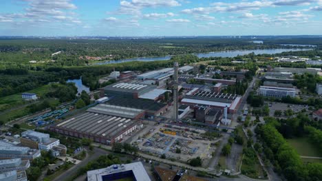 hennigsdorf industrial area with modern offices, old factory buildings and chimneys under blue sky. best aerial view flight fly reverse drone