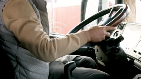 the camera focuses on the hands of an older worker on stick shift and steering wheel of a truck 1