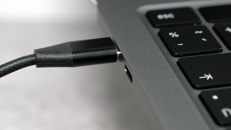 cerca de la mano de la mujer sacar el cable usb tipo c de la computadora portátil