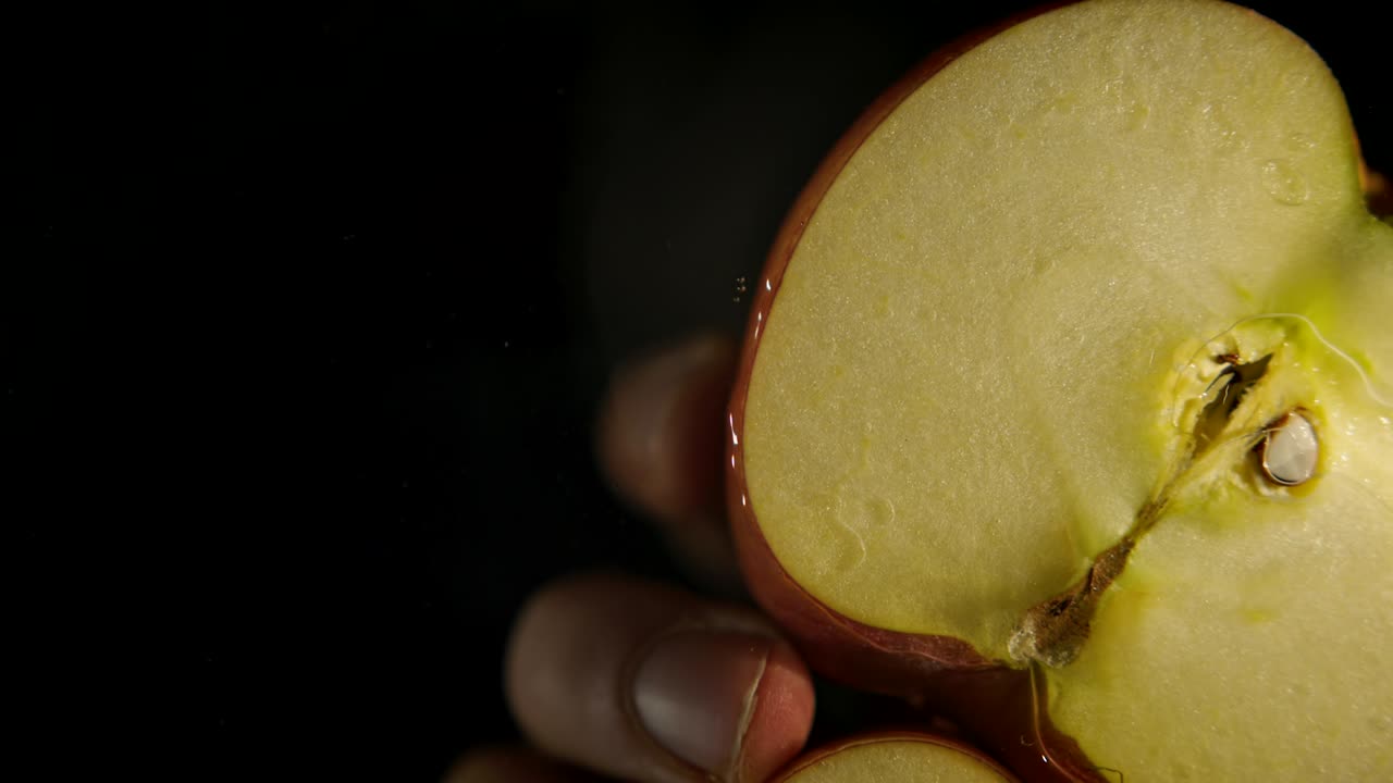 vista de abajo de una manzana roja fresca cortada en dos mitades en agua con fondo negro. estudio de rodaje 4k.