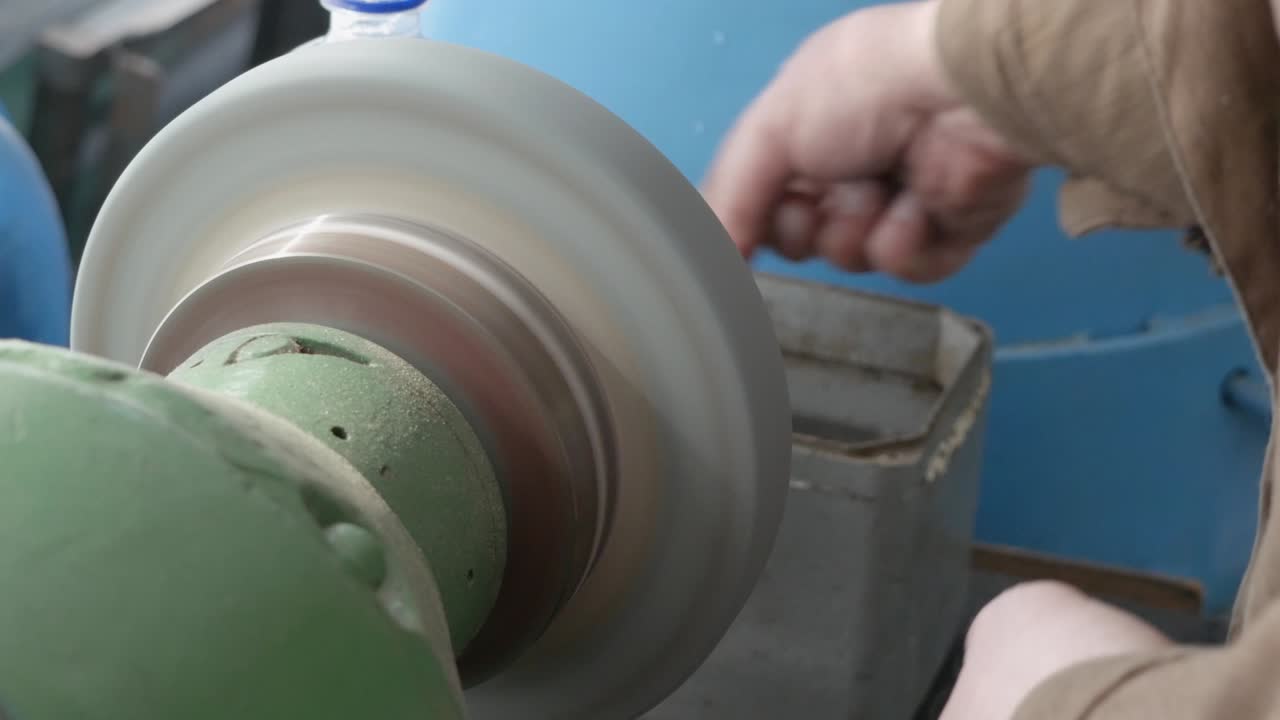 은 손의 마스터는 벤치 그린더, 거친 그린더 머신, 클로즈업, 피데스탈 그린더 작업, 물건 생산, 공장에서 금속 부품을 마무리 는 작업을 수행합니다.