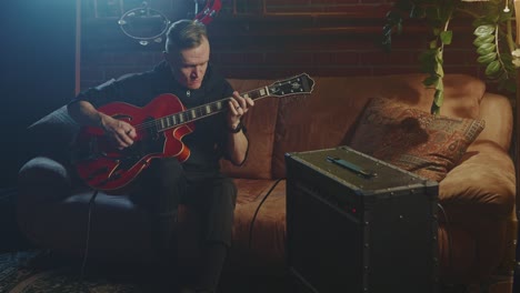 man playing a red jazz guitar in a home studio