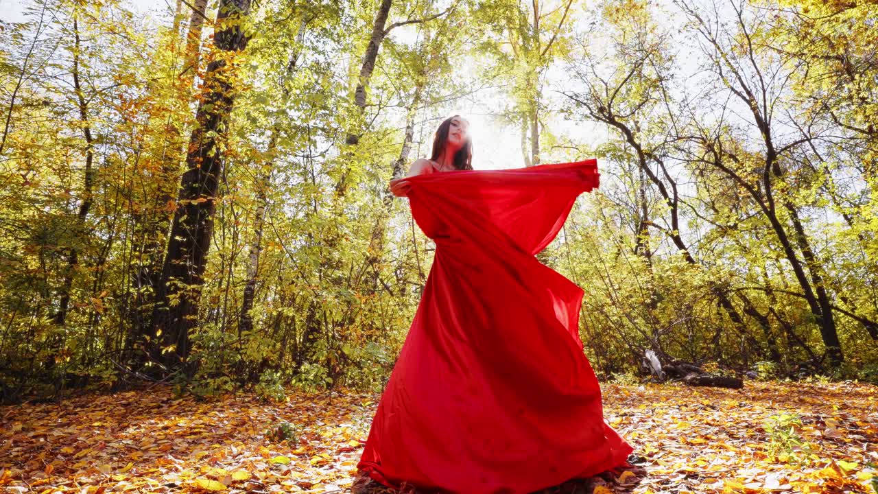A Captivating Dance in Autumn: A Stunning Display of Grace and Elegance as a Figure in a Flowing Red Dress Dances Amidst the Golden Leaves Under a Shimmering Sunlight