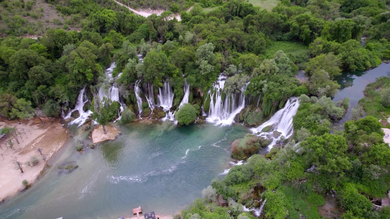 La Cascata di Kravica forma un ampio bacino turchese in mezzo a una foresta lussureggiante in Erzegovina, vista aerea con rotazione a destra