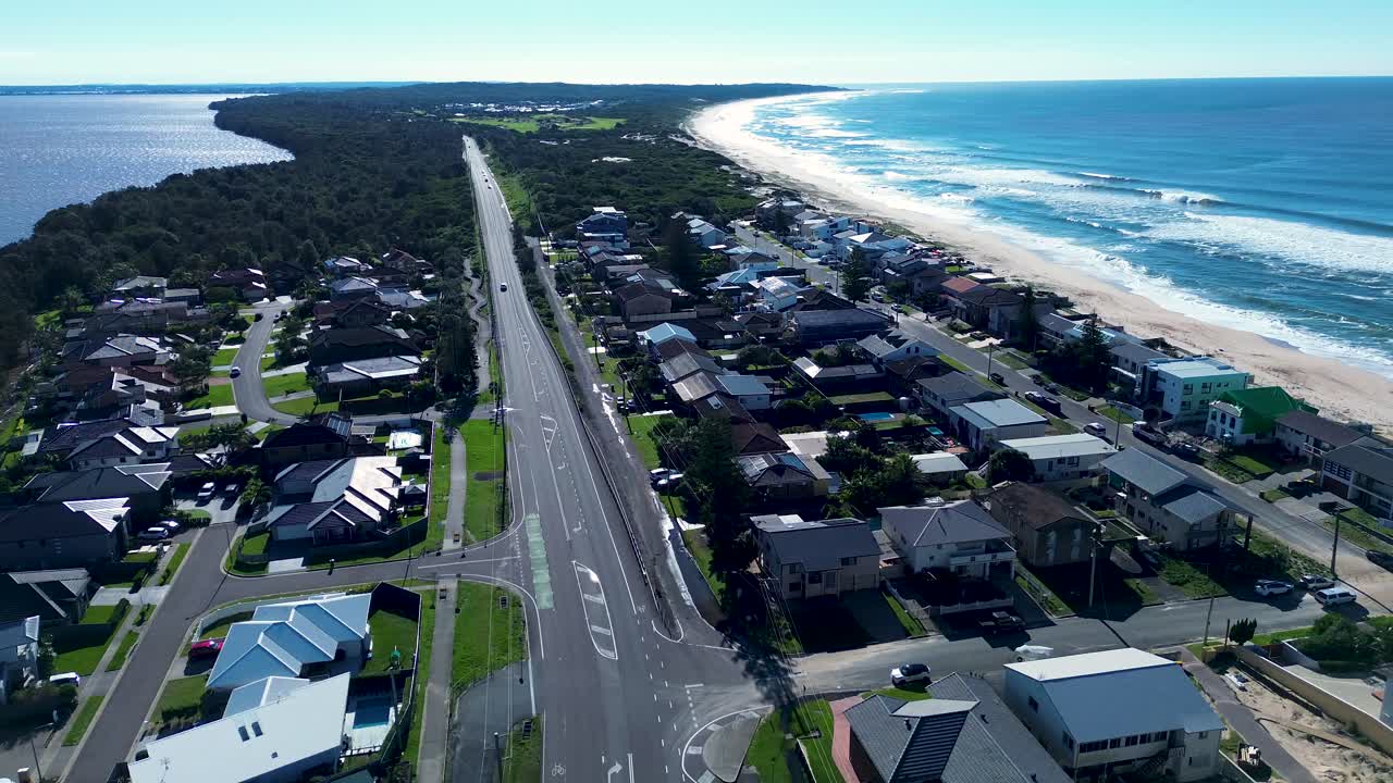 Drone aerial landscape of main road highway and local housing town suburbs with waves breaking at ocean beach of North Entrance Norah Head Central Coast Australia infrastructure outdoors coastline