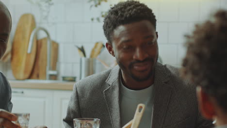 black parents and children speaking at dinner table during family celebration