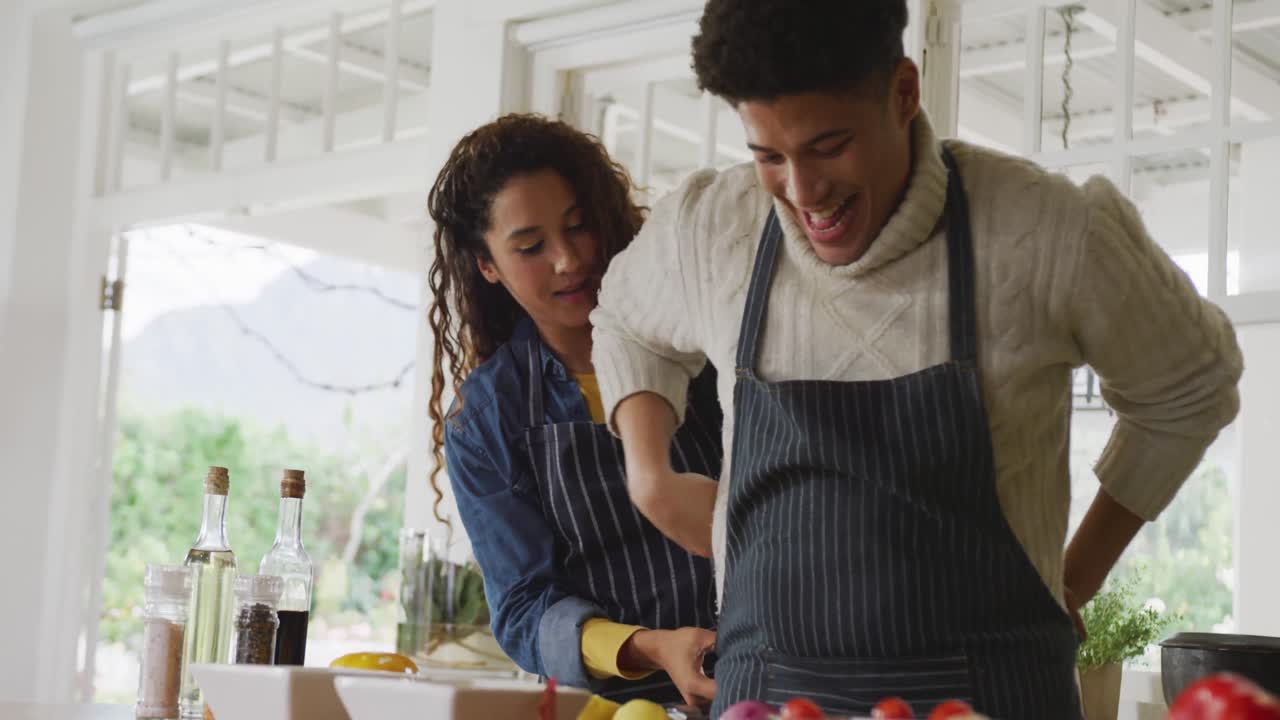 video de hombres biraciales felices preparando comida en la cocina