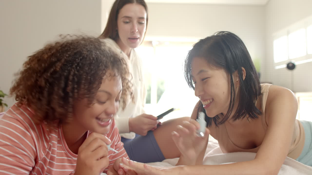 Painting nails and chatting, three women friends enjoying time together at home
