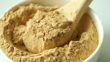 brown powder in a bowl with wooden spoon