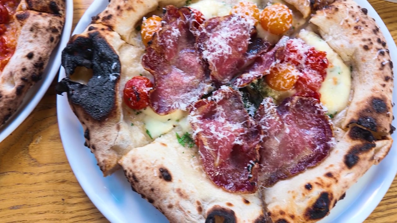 Due pizze gourmet cotte a legna su un tavolo di legno