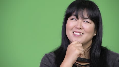 Head shot of happy overweight Asian woman thinking