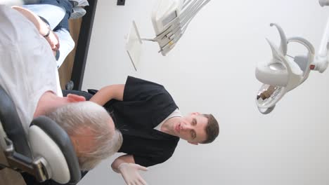 an old man sits on a dental chair and listens to a dentist. implantation of teeth for pensioners.