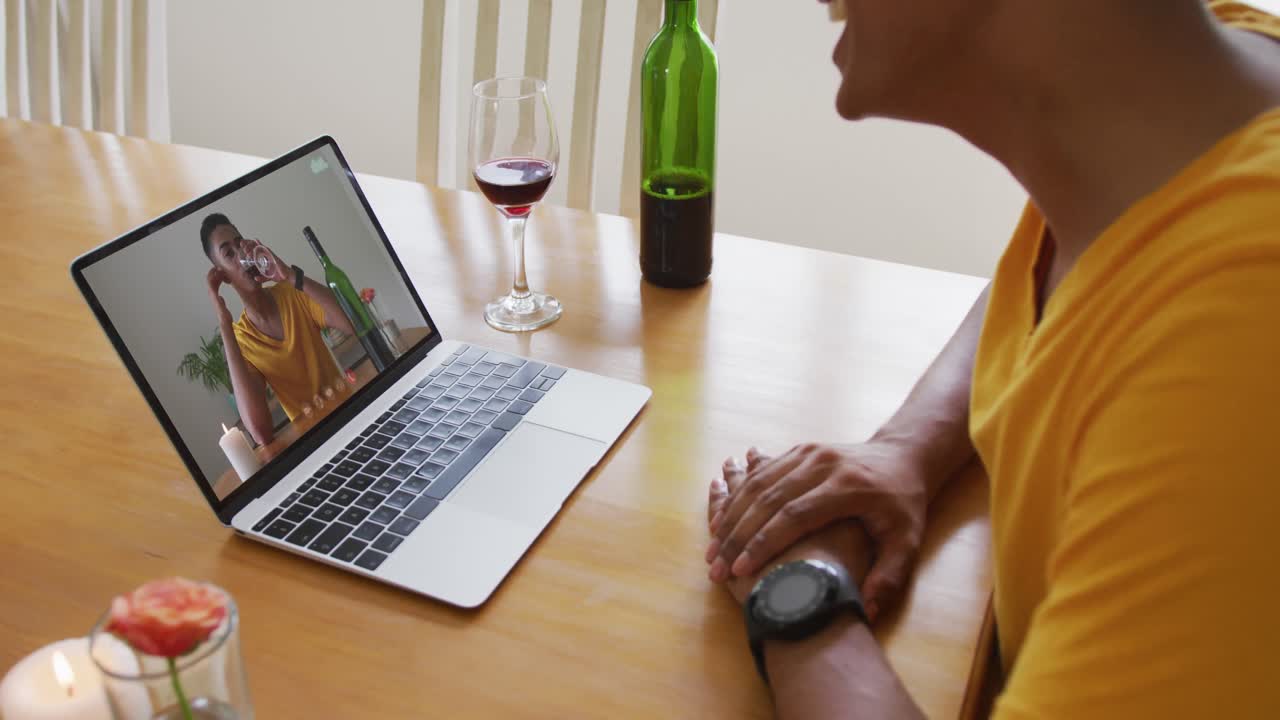 Mid section of african american man with wine while having a video call on laptop at home