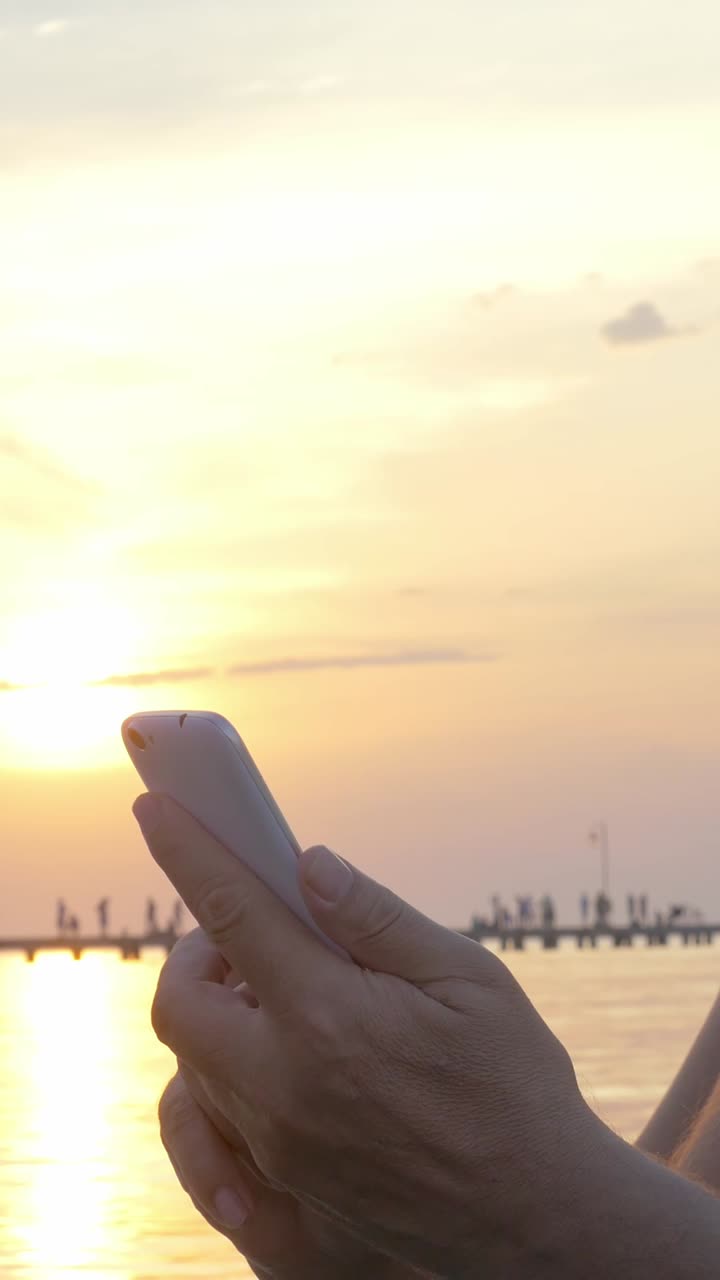 Using smartphone at sunset on pier