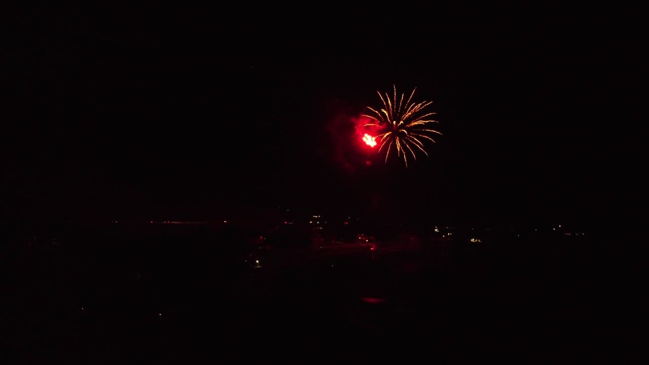 clip largo y lento mientras el dron vuela lentamente hacia la explosión de fuegos artificiales sobre el lago para ver hermosos colores por la noche en la oscuridad
