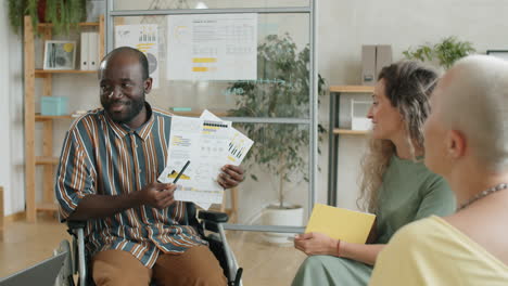 african american man with disability discussing business report with colleagues