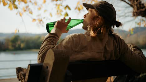 wandelaar dorstig na lange reis drinkwater uit groene fles voor landschap, dürnstein