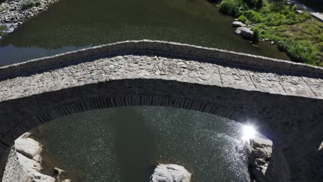 Pedestal-drone-shot-of-the-main-arch-of-Devil's-Bridge-and-the-Arda-River,-located-in-the-town-of-Ardino-at-the-foot-of-Rhodope-Mountain-in-Bulgaria