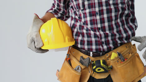 Architect-with-tool-belt-and-holding-hard-hat-against-white-background-4K-4k