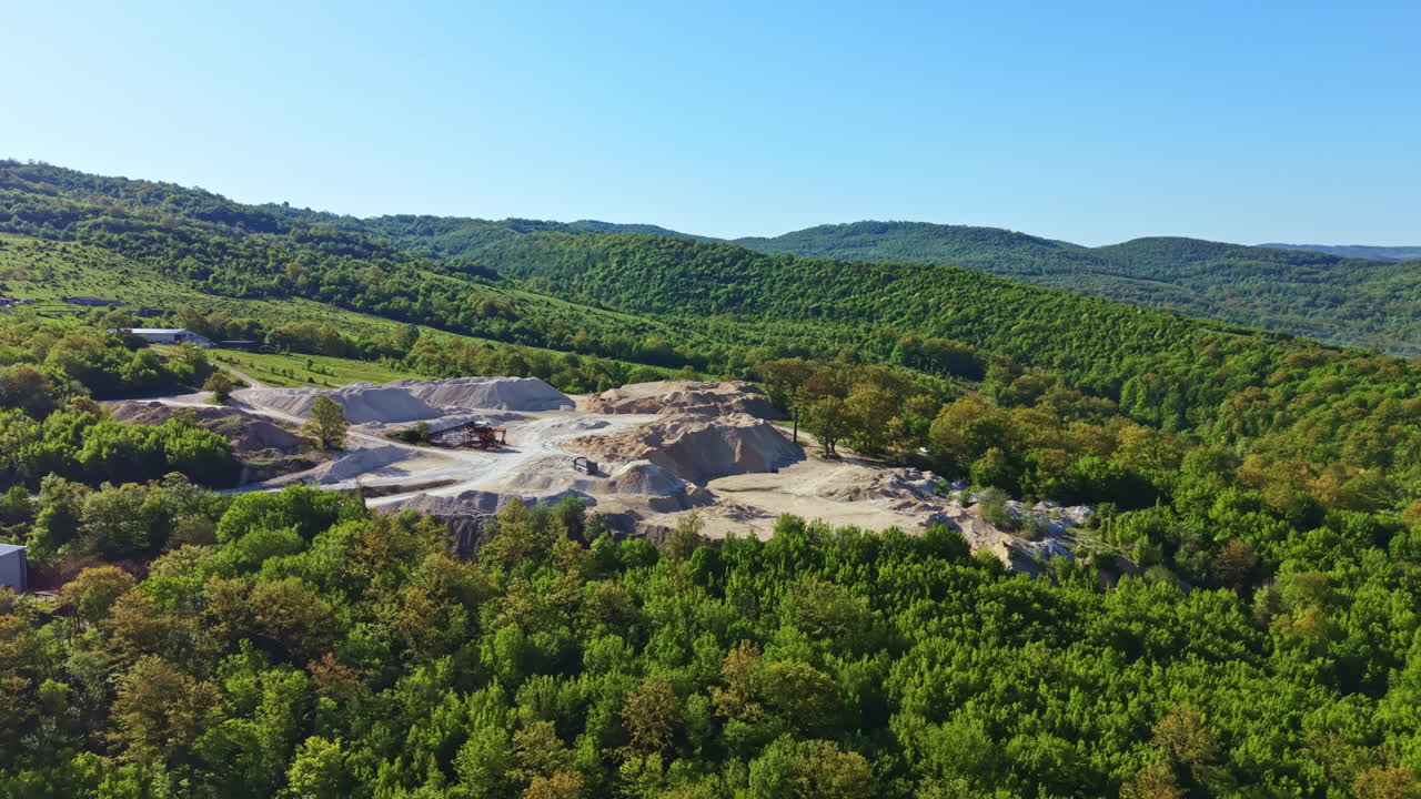 Sito minerario in un'area boschiva con colline e montagne sullo sfondo in una giornata di sole
