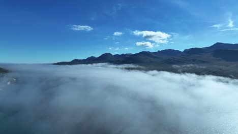 aerial view over low clouds at faskrudsfjordur fjord in east iceland - drone shot