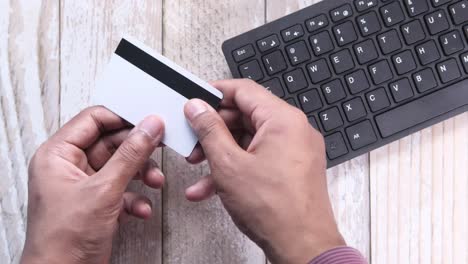 person using a credit card and keyboard for online transaction