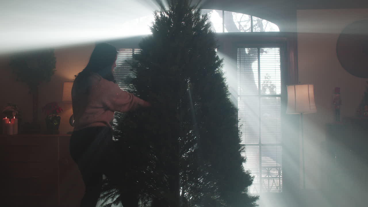 Woman Decorating a Christmas Tree with Light Beams