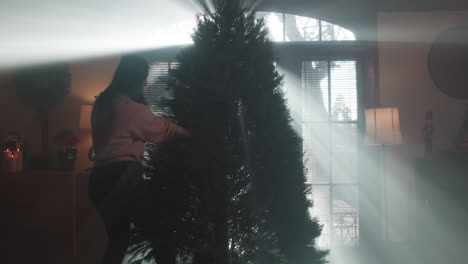 woman decorating a christmas tree with light beams