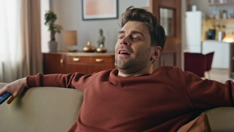 relaxed hipster falling sofa holding cellphone in modern apartment close up.