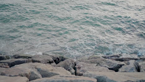 Turquoise-waves-splash-against-rocky-shore,-capturing-the-serene-beauty-of-the-ocean