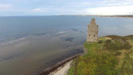 Ruins-of-ancient-Scottish-castle-on-headland-facing-lake