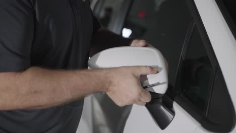 Unrecognizable-mechanic-removing-car-side-mirror-cap-during-repair,-slow-motion