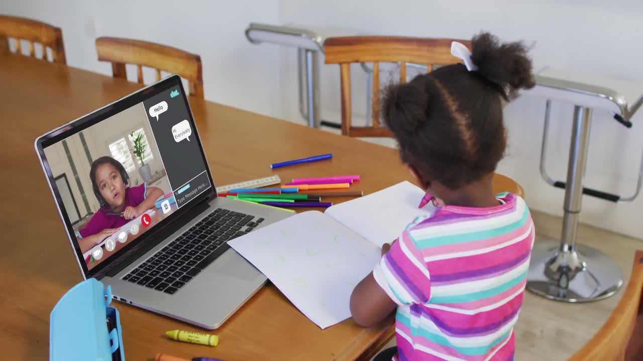 Schoolgirl using laptop for online lesson at home, with her school friend and web chat on screen