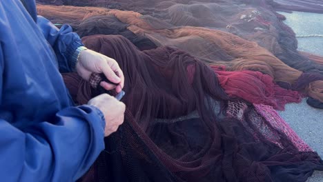 a person is using a knife to cut through a fishing net, capturing the essence of a maritime atmosphere and the quaint village life in a small fishing town