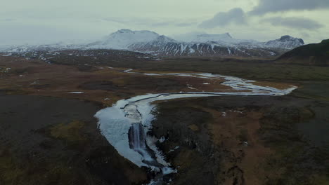 aerial view of svodufoss waterfall and snaefellsjokull stratovolcano at winter in iceland