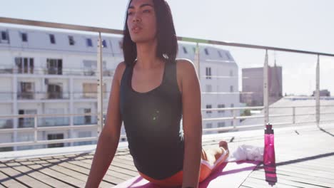 Mixed-race-gender-fluid-person-practicing-yoga-meditation-on-roof-terrace