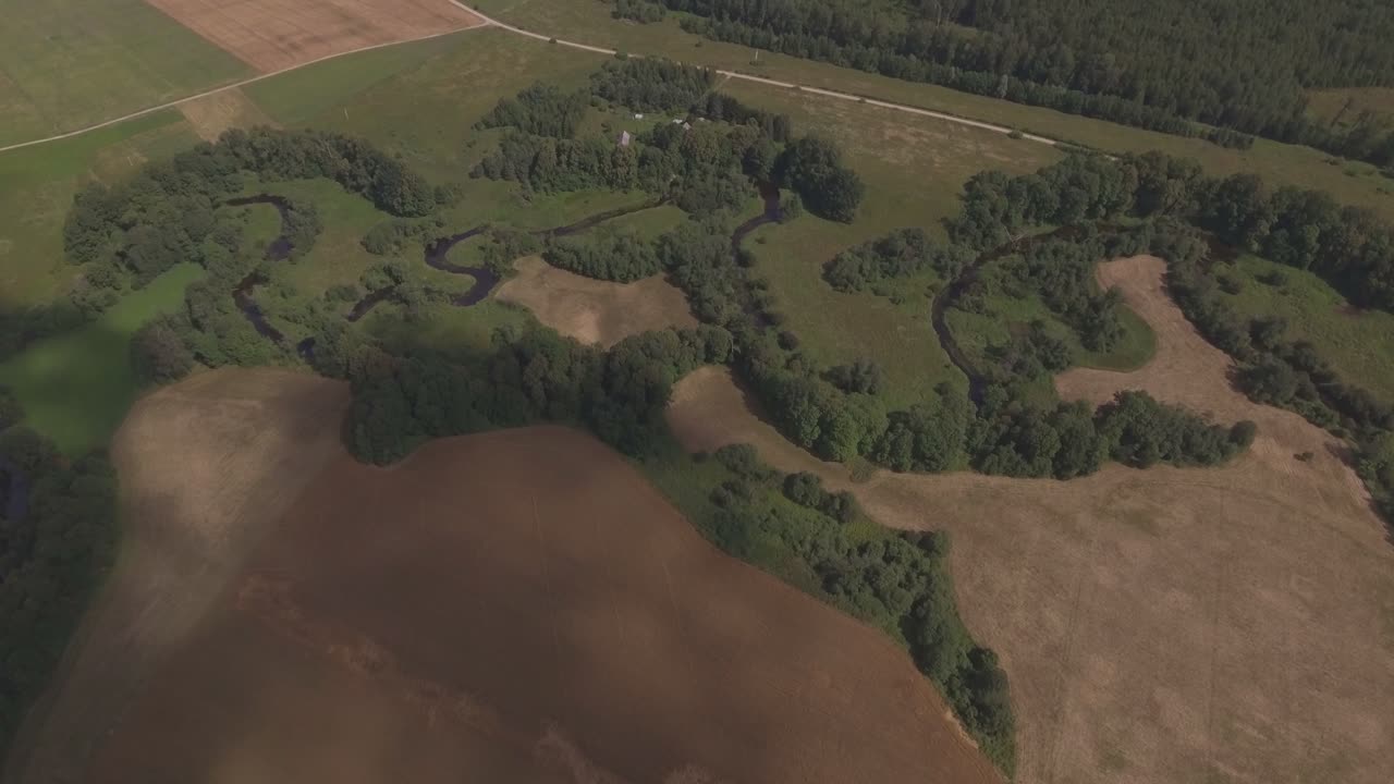 Sirvinta River Winds Between Green Fields And Trees. Aerial Forward