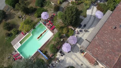 Vista-Superior-De-Drones-De-Una-Casa-De-Vacaciones-Con-Piscina-Y-Sombrillas-En-El-Campo-Italiano,-Antena