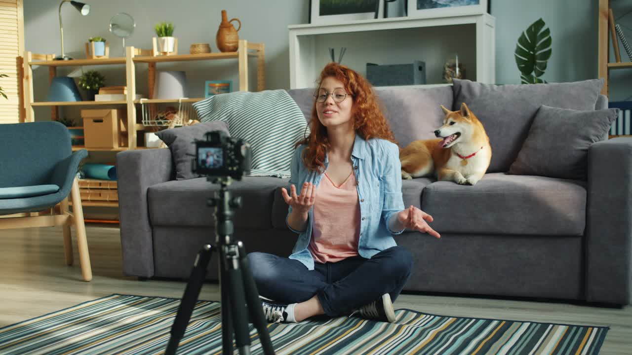 cámara lenta de una vlogger femenina grabando video en casa con un lindo perro