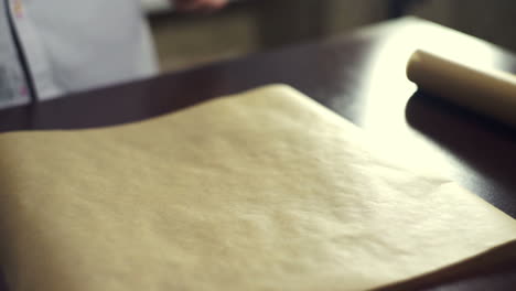 preparing for baking cake. cook putting baking paper on baking pan