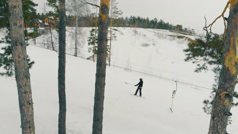 skier-holds-surface-lift-poma-on-snowy-hill-bird-eye-view