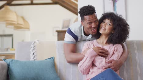 happy african american couple embracing together in living room