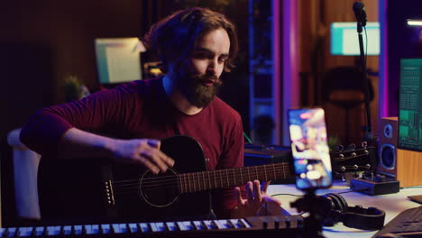 artist recording himself at home singing and playing acoustic guitar