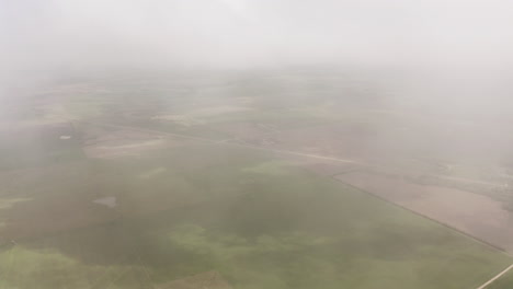 Aerial-drone-moves-through-clouds-above-grassland-and-farmland-in-midwest-of-United-States