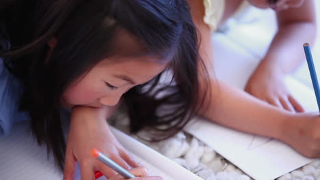 Two-children-colouring-as-they-lie-next-to-each-other