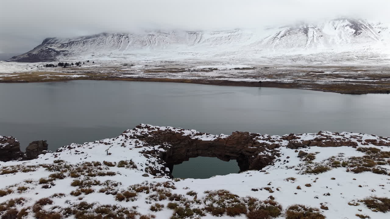 Natural stone bridge covered in snow with a lake and mountains in Caviahue